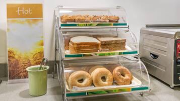 A bakery display case with muffins, sandwiches, and bagels.