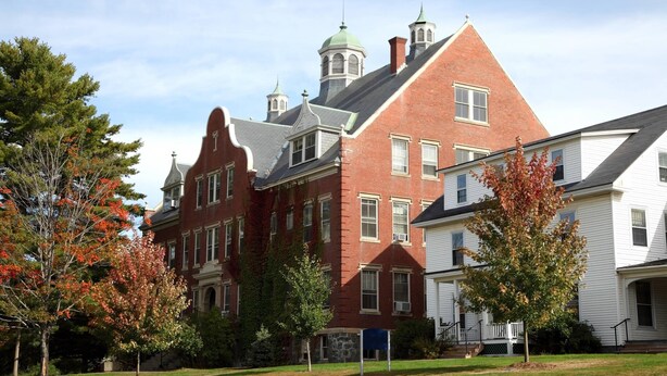 A historic building with a prominent red brick facade, multiple windows, and a green dome on the roof.