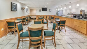 A restaurant with wooden tables and chairs, a counter with food display, and a TV mounted on the wall.