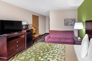 A hotel room with a television, a microwave, a sofa, a bed, a desk, and a dresser. - Econo Lodge Inn & Suites Oconto (Oconto)