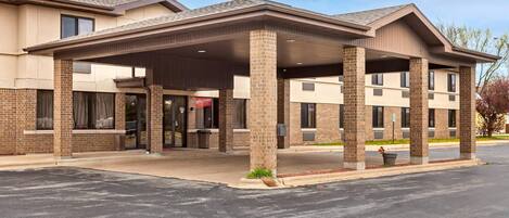 A two-story hotel with a covered entrance, brick facade, and a parking lot.