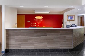 A reception desk with a red wall, a wooden counter, and a ceiling with recessed lighting. - Econo Lodge Inn & Suites Oconto (Oconto)