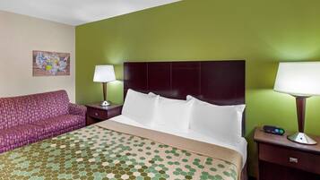 Une chambre d’hôtel avec un lit, un mur vert, un canapé violet et une table de chevet avec une lampe.