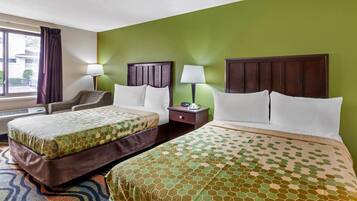 Habitación de hotel con dos camas, una silla, una mesita de noche con lámpara y una ventana con cortinas.