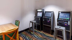 A room with three slot machines, a wooden table, and a green chair. - Econo Lodge Inn & Suites Oconto (Oconto)