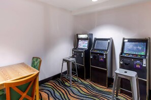 A room with three slot machines, a wooden table, and a green chair. - Econo Lodge Inn & Suites Oconto (Oconto)