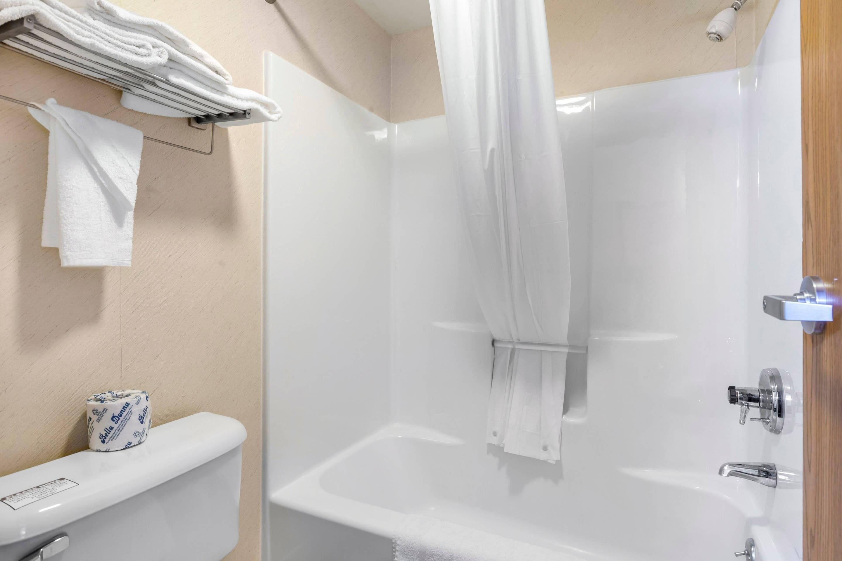 Ein Badezimmer mit einer Badewanne, Toilette und einem Handtuchhalter mit Handtüchern.