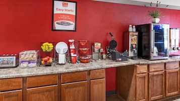 A kitchen counter with a toaster, a waffle maker, a coffee machine, and a refrigerator.