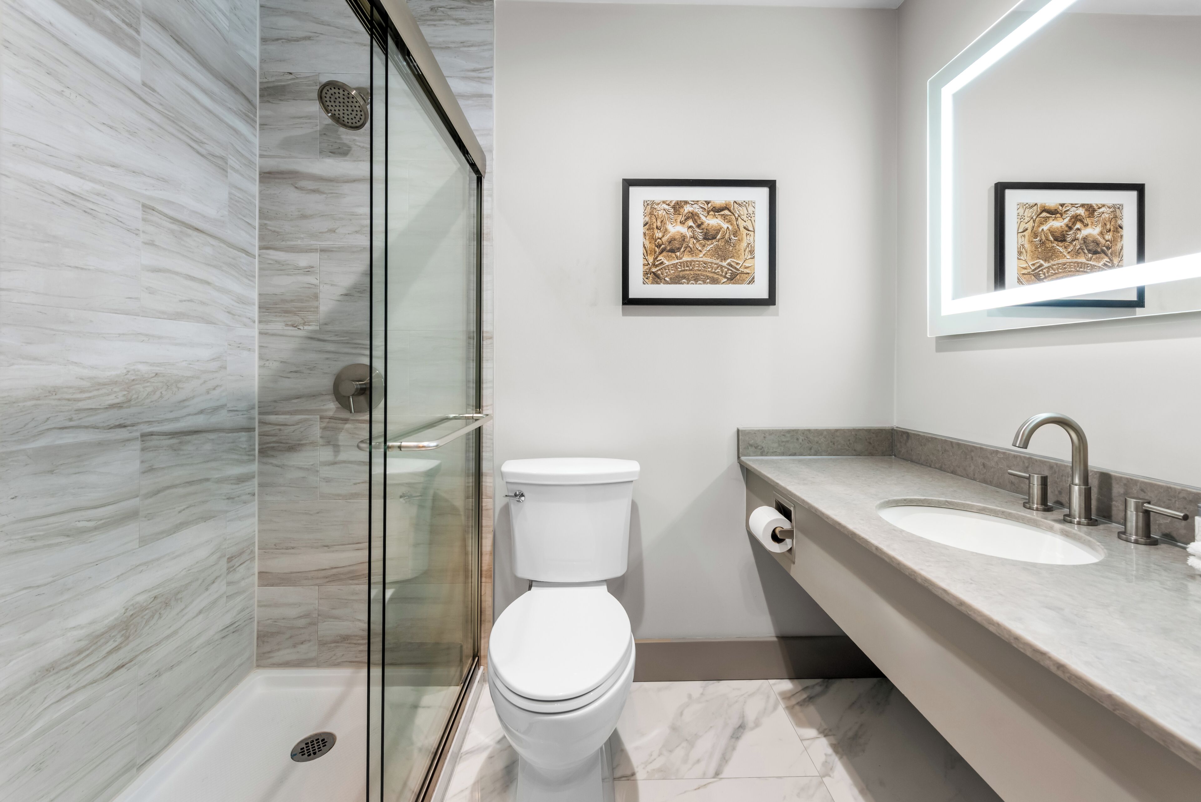 A modern bathroom with a glass shower enclosure, a white toilet, and a marble-tiled floor.