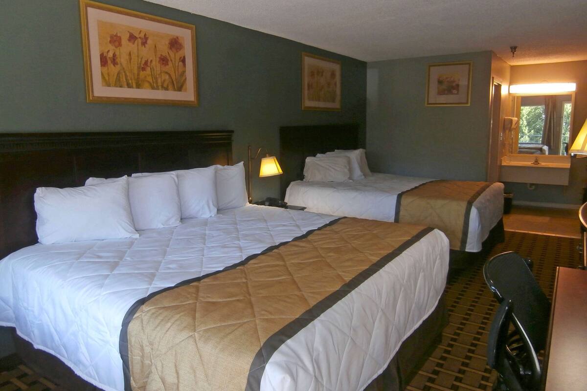 Een hotelkamer met twee bedden, een bureau en een stoel.