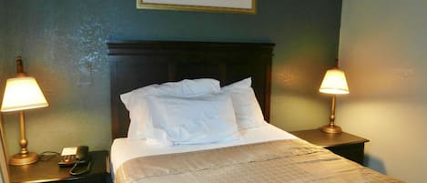Una cama bien hecha con sábanas blancas, dos lámparas de noche, un teléfono y una obra de arte floral enmarcada en la pared.