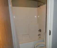 A bathroom with a bathtub, toilet, and shower.