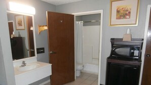 Baño con lavamanos, inodoro, ducha y microondas.