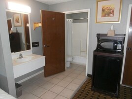 A bathroom with a sink, toilet, shower, and a microwave.