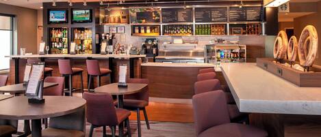 A modern bar area with multiple seating options, a variety of liquor bottles, and a television screen.