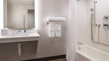A modern bathroom with a white sink, mirror, and a shower area with a bathtub.
