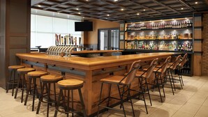 Eine Bar mit einer langen Theke, mehreren Hockstühlen und einer Weinauslage.