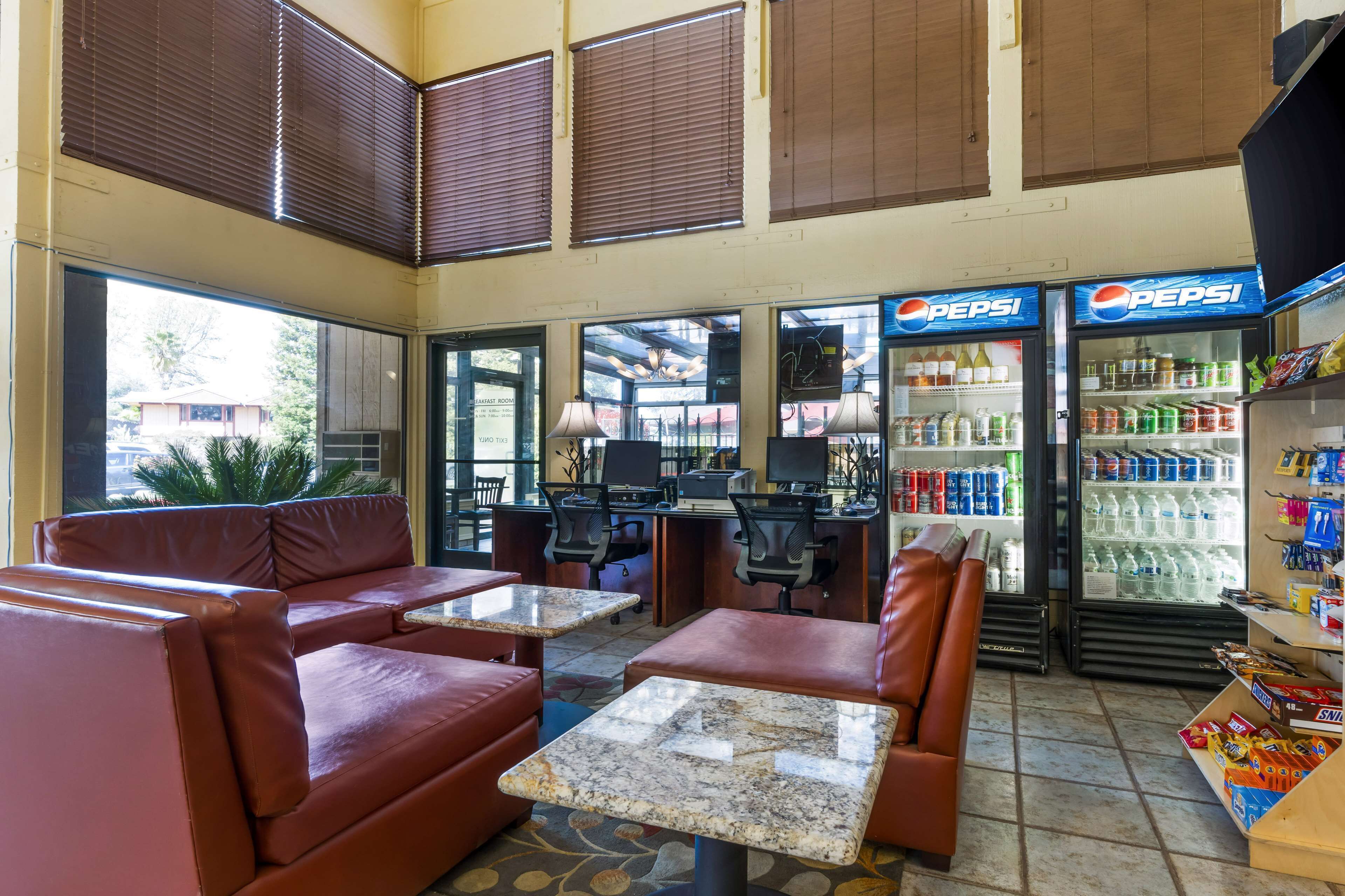 A lobby with seating, a Pepsi refrigerator, and a counter with various items.