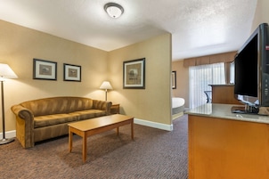 Habitación de hotel con sofá, mesa de centro, televisor y cuadros en la pared.