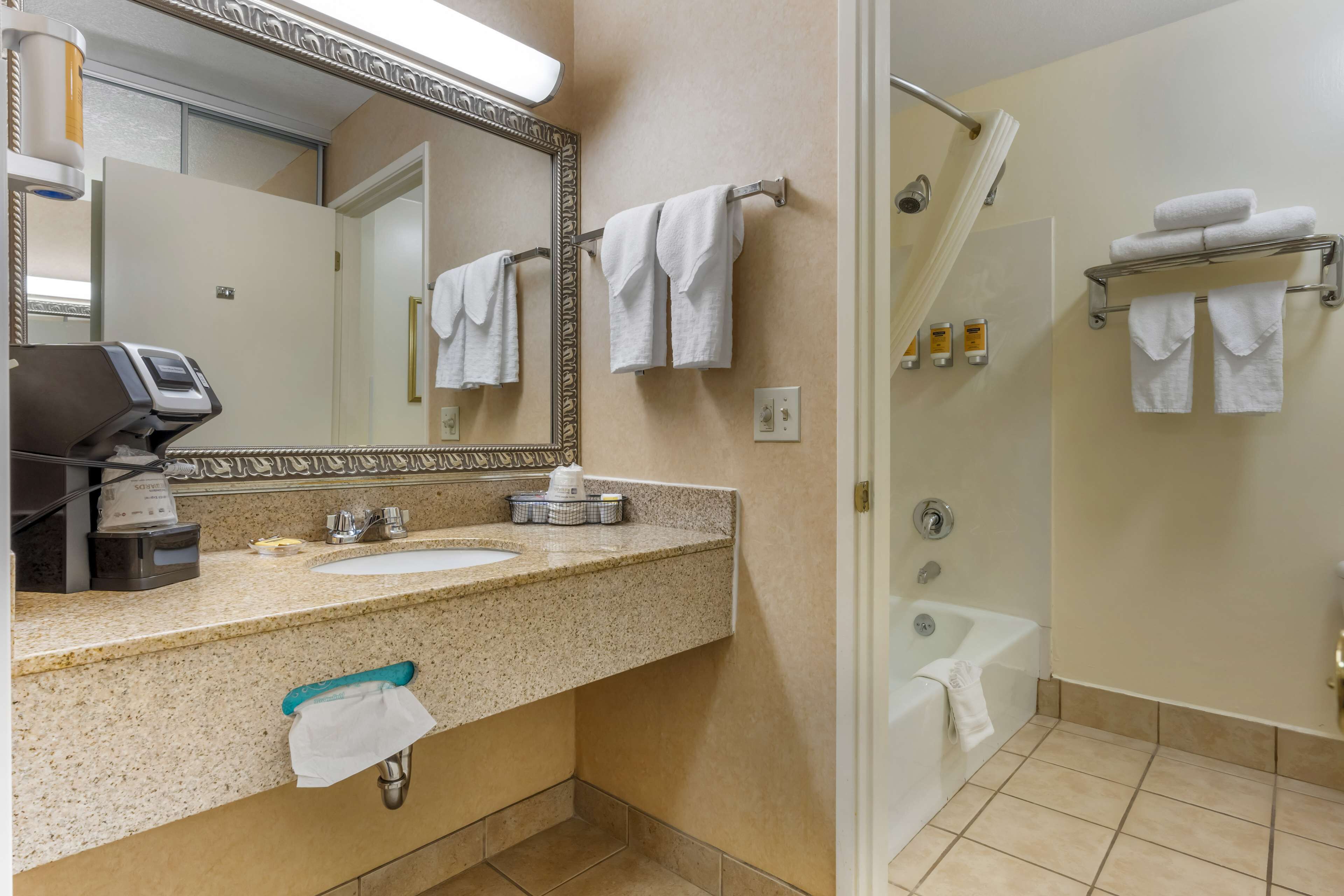 A bathroom with a sink, mirror, towel rack, and a shower area.