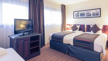 A hotel room with a bed, a TV on a wooden stand, and a framed picture on the wall.