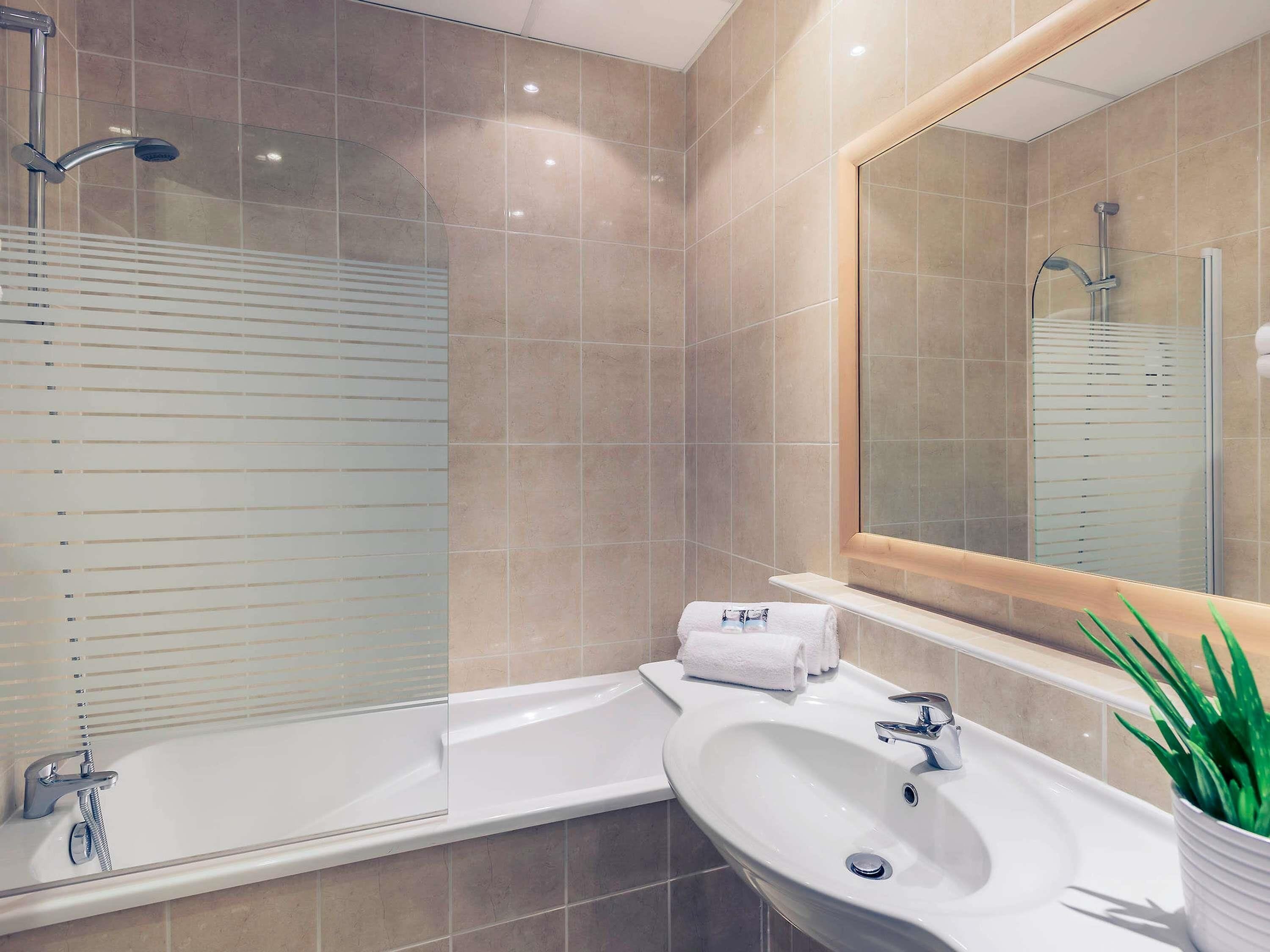 A modern bathroom with a bathtub, a sink, and a large mirror.