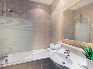 Un bagno moderno con una vasca, un lavandino e un grande specchio.