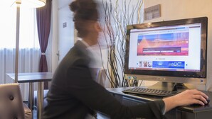 Une personne travaillant à un bureau équipé d’un ordinateur, d’une lampe et d’un panneau indiquant un espace dédié aux activités professionnelles.