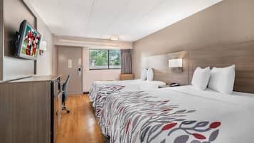 A hotel room with a bed, bedside table, lamp, and a television mounted on the wall.