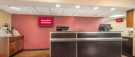 A reception area with a counter, a coffee machine, and a sign indicating free Wi-Fi in all rooms.
