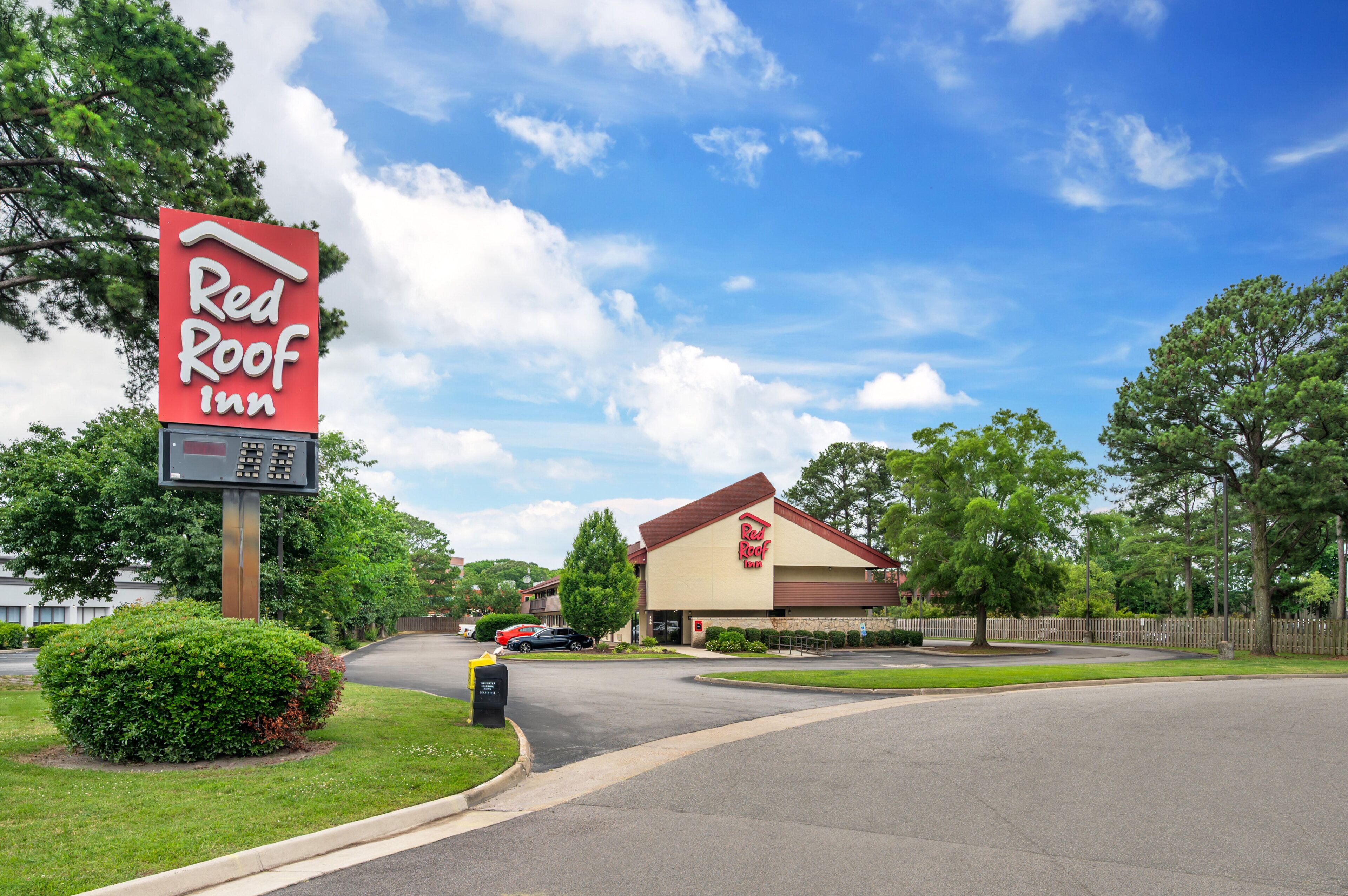 Un Red Roof Inn con un letrero grande, un estacionamiento y un césped bien cuidado.