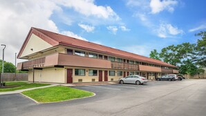 A multi-story motel with a red roof, a parking lot, and a small grassy area in front. - Red Roof Inn Virginia Beach (Virginia Beach)