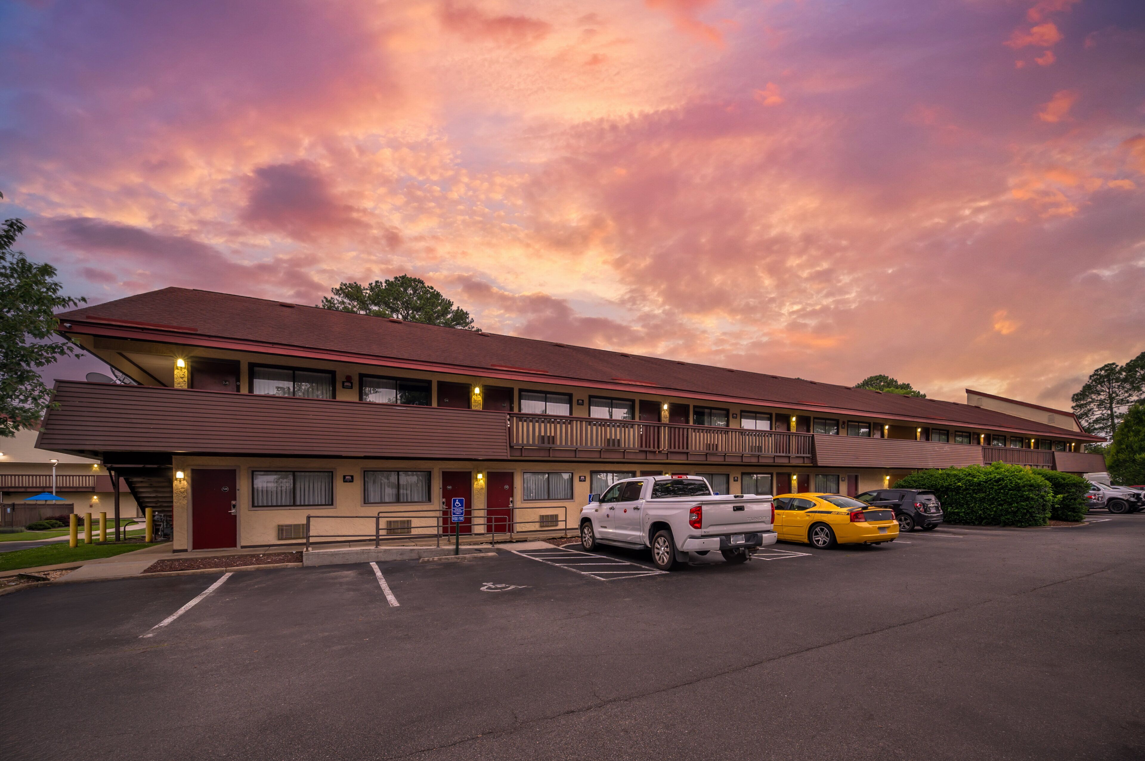 A motel with a parking lot, a red door, and a sign indicating handicap accessibility.