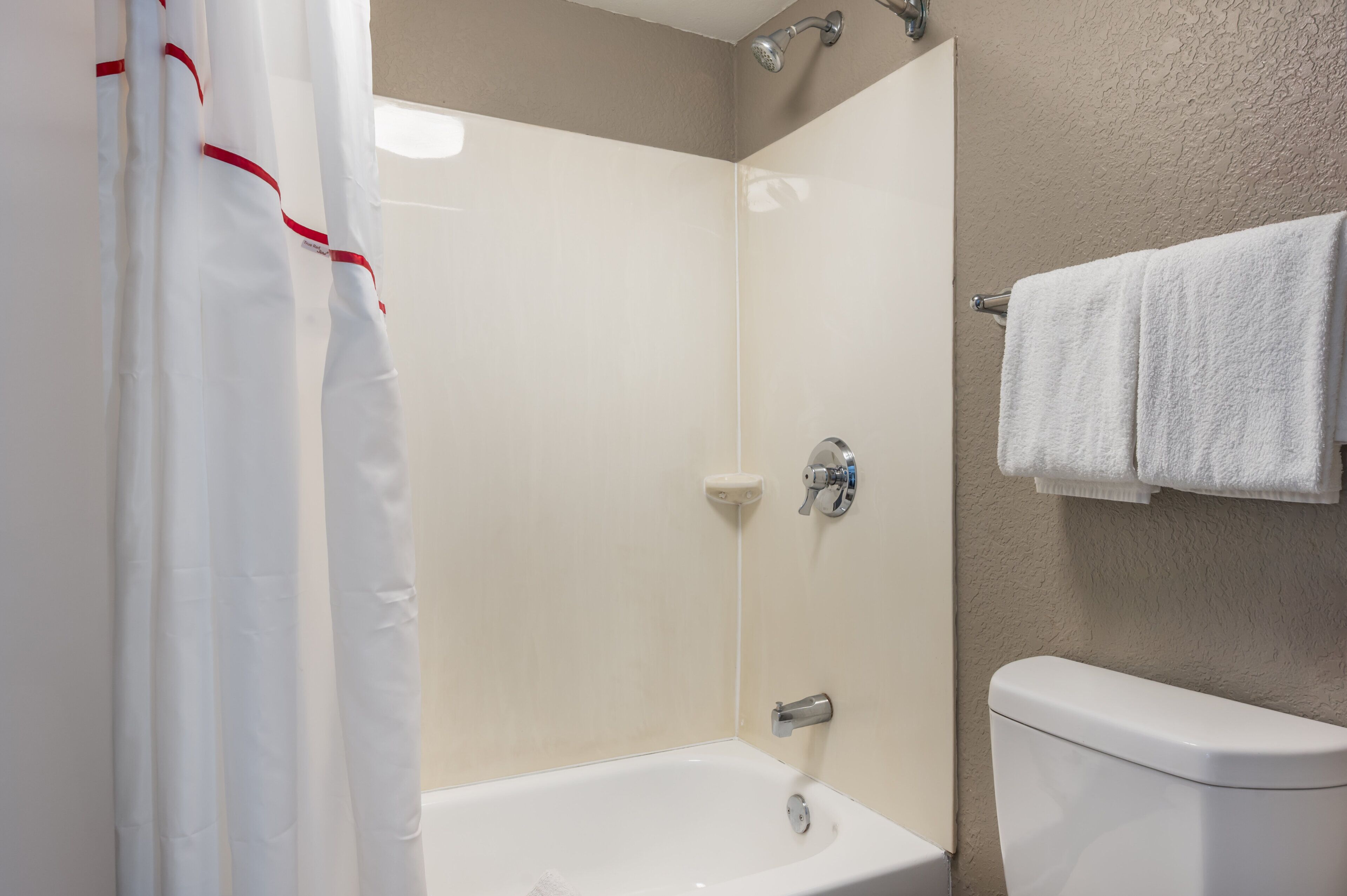 Un baño con bañera, inodoro y cortina de ducha.