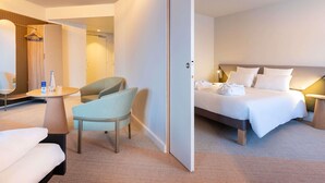 A hotel room with a bed, a chair, a small table, and a wardrobe.