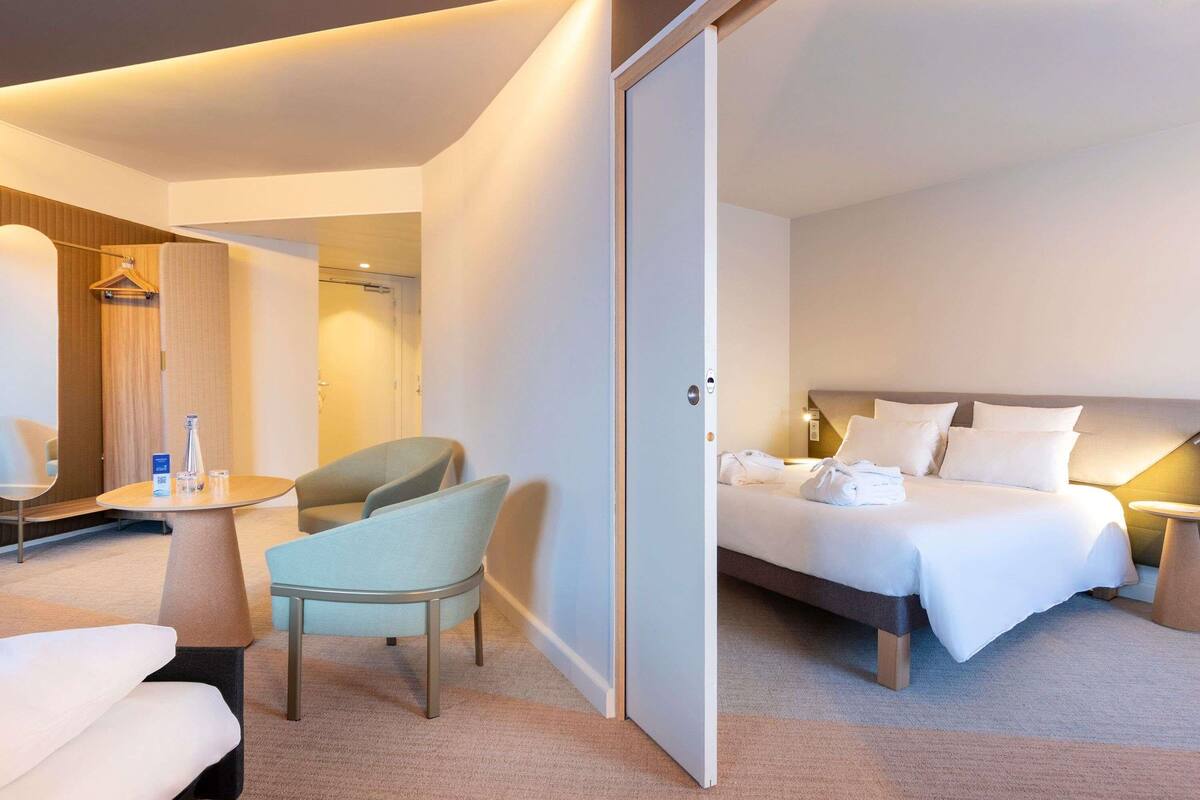 Een hotelkamer met een bed, een stoel, een klein tafeltje en een kledingkast.