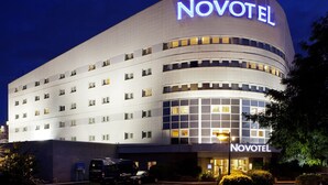 A modern hotel with a curved facade and a prominent 'Novotel' sign.