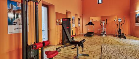 Une salle de sport équipée de matériel d’exercice, dotée d’un plancher en bois et d’un tapis à motifs.
