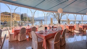 Ein Restaurant mit gedeckten Tischen mit Blick auf ein Gewässer und eine Berglandschaft.