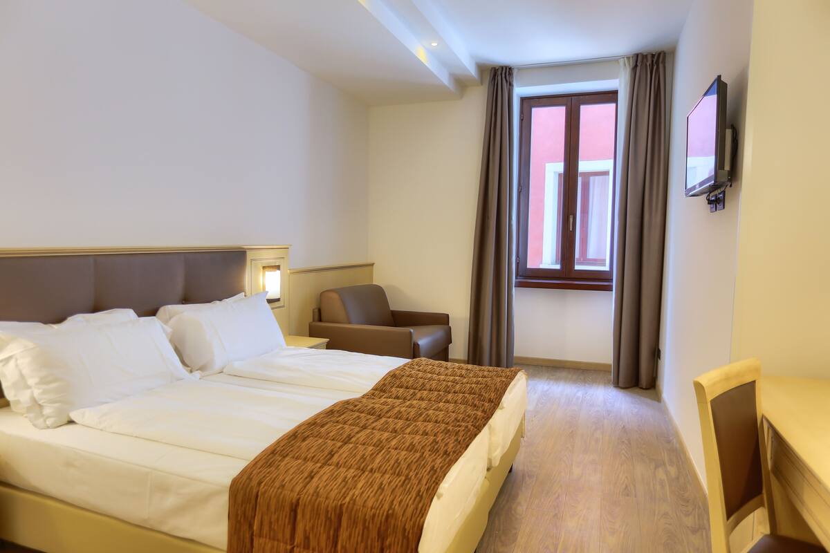 Ein Hotelzimmer mit Bett, Stuhl, Schreibtisch und Fernseher.