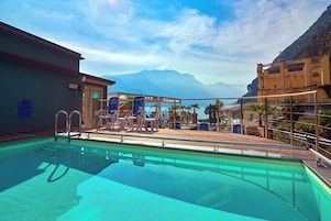 Una piscina al aire libre, sombrillas, sillones reclinables de piscina