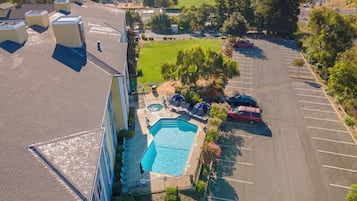 An aerial view of a residential area with a swimming pool, a parking lot, and a building with multiple air conditioning units on the roof.