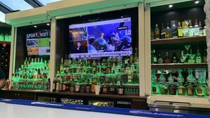 A bar area with a large screen displaying sports content, shelves of various liquor bottles, and a sign for 'SPORT MIX'. - Comfort Inn Metro Airport (Romulus)