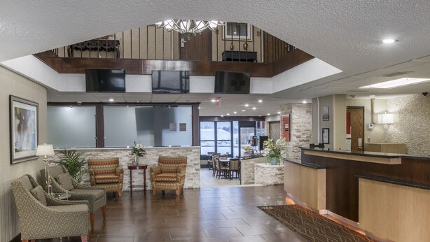 A spacious lobby with a high ceiling, a reception desk, comfortable seating, and a view to the outside. - Comfort Inn Metro Airport (Romulus)