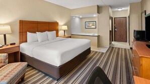 A hotel room with a large bed, two bedside tables with lamps, a TV, a desk with a chair, a bathroom with a shower, and a door. - Comfort Inn Metro Airport (Romulus)