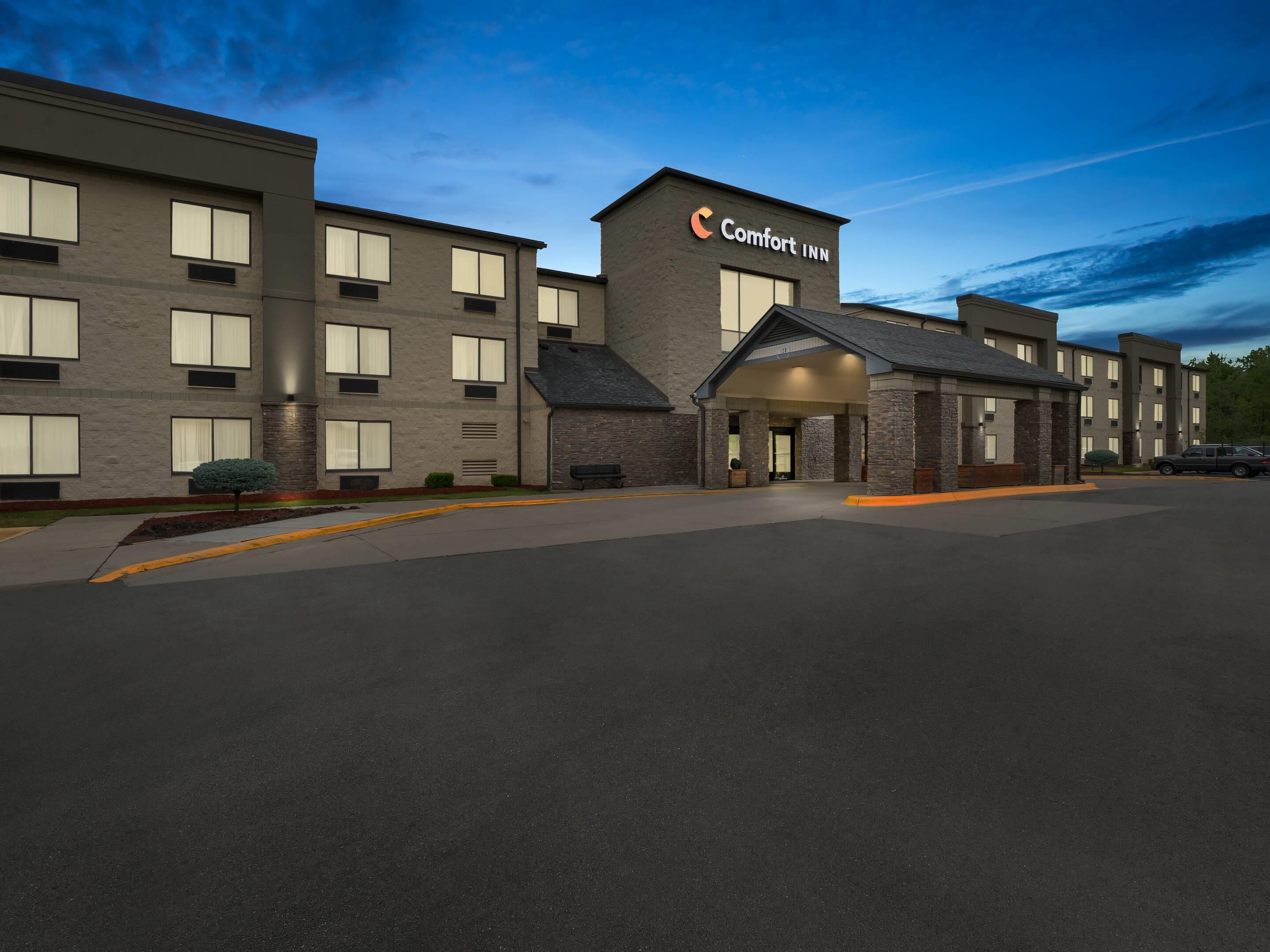 A Comfort Inn hotel with a modern design, featuring a large parking lot and a well-lit entrance.