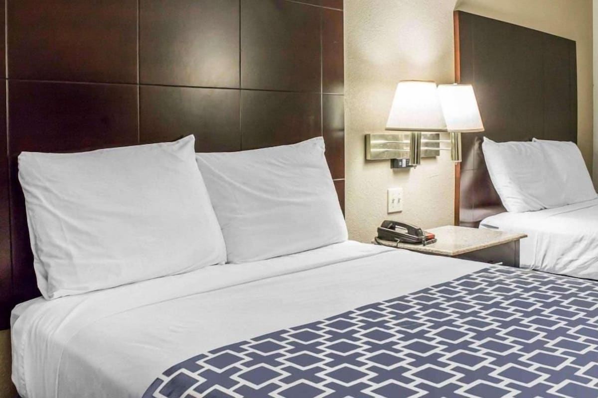 A hotel room with a large bed, a bedside table with a lamp, and a telephone.