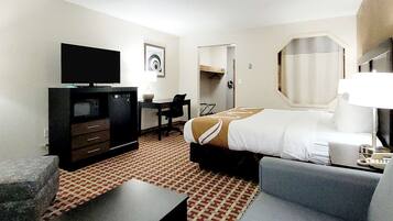 A hotel room with a bed, a desk, a television, a chair, and a small table.