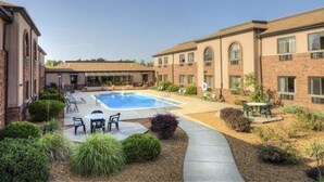 A courtyard with a swimming pool, outdoor seating, and a building with multiple windows and arches. - Quality Inn & Suites Marion (Marion)