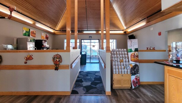 A hotel lobby with wooden beams, a reception desk, a coffee machine, and a display of food items. - Quality Inn & Suites Marion (Marion)
